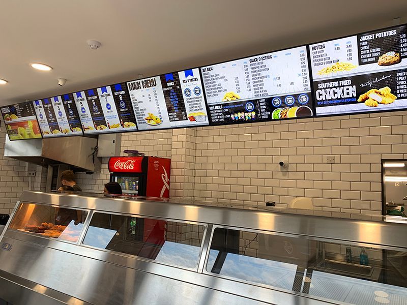 A stainless steel counter in a restaurant with a coca cola refrigerator.