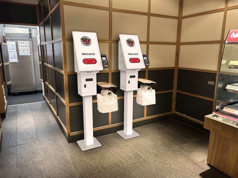 Two white kiosks are sitting next to each other in a room.