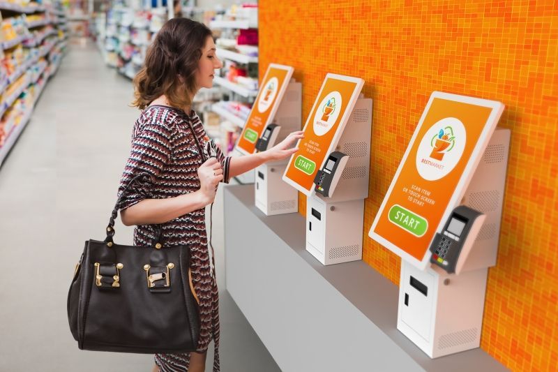 A woman is using a self service machine in a grocery store.