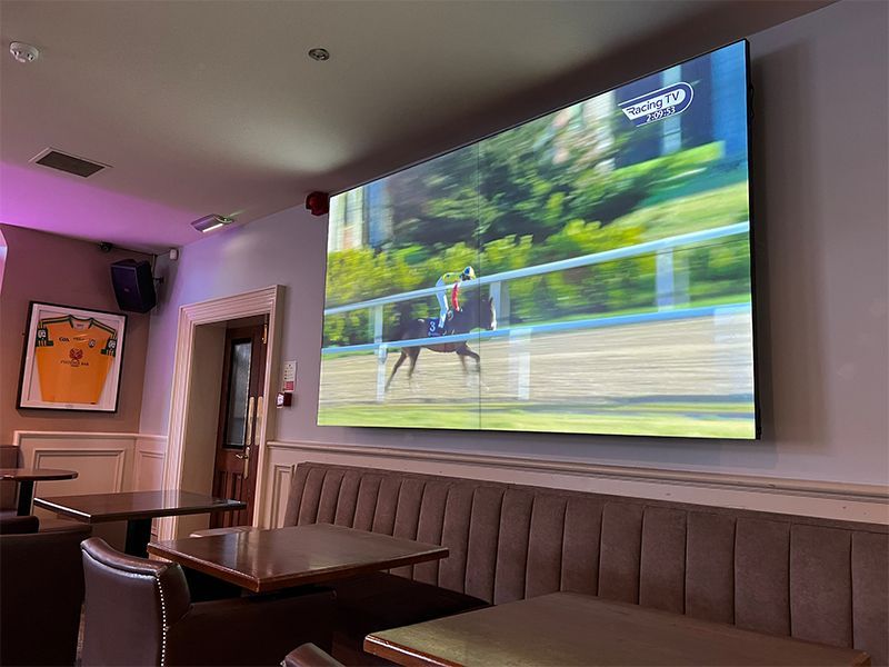 A large screen is hanging on the wall in a restaurant.