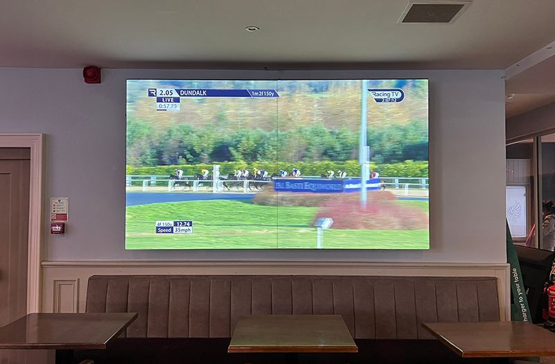 A large screen is hanging on a wall in a restaurant.