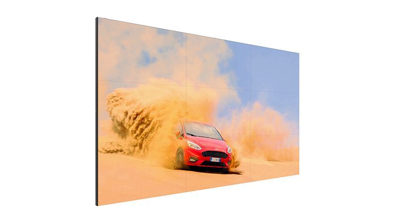 A red car is driving through the sand in the desert.