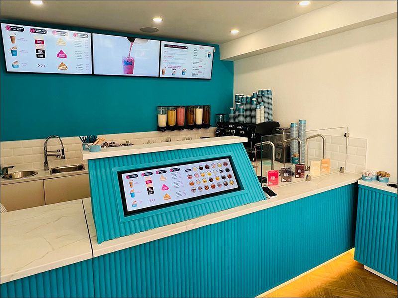 A restaurant with a blue counter and a menu on the wall.