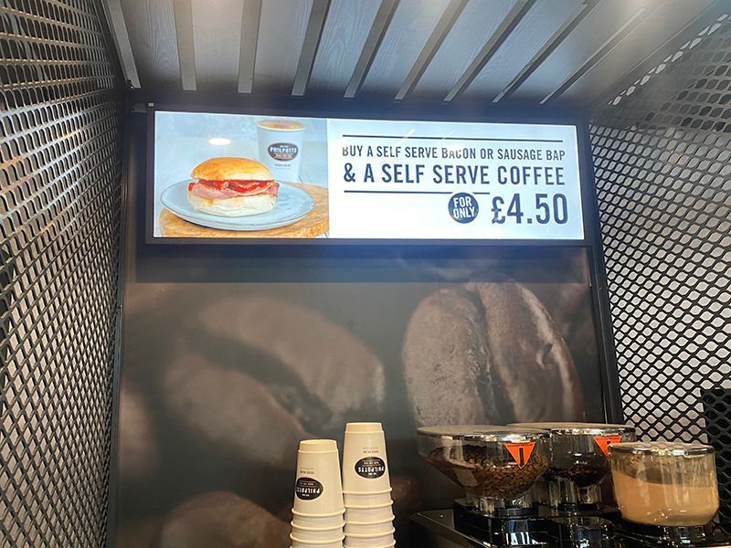 A sign in a restaurant advertising a sandwich and a self serve coffee.