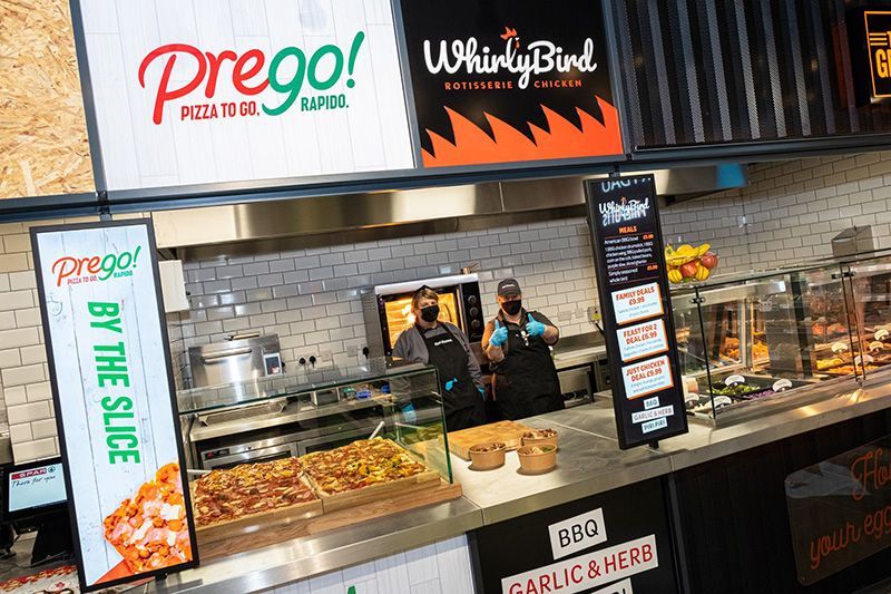 A restaurant with a buffet line and a sign that says prego by the slice.