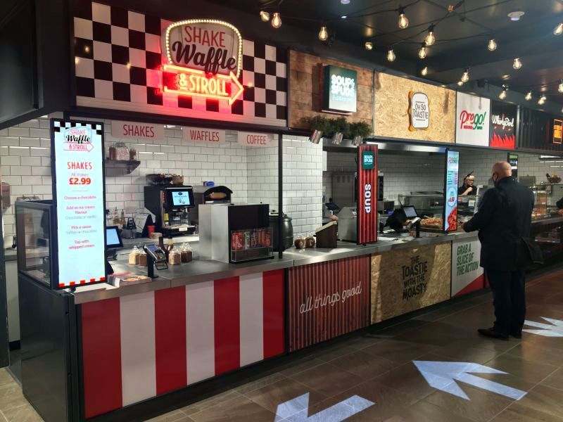 A man is standing at a counter in a restaurant.