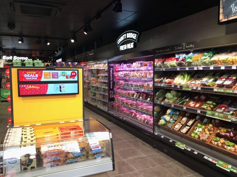 A grocery store with a lot of shelves and a tv on the wall.
