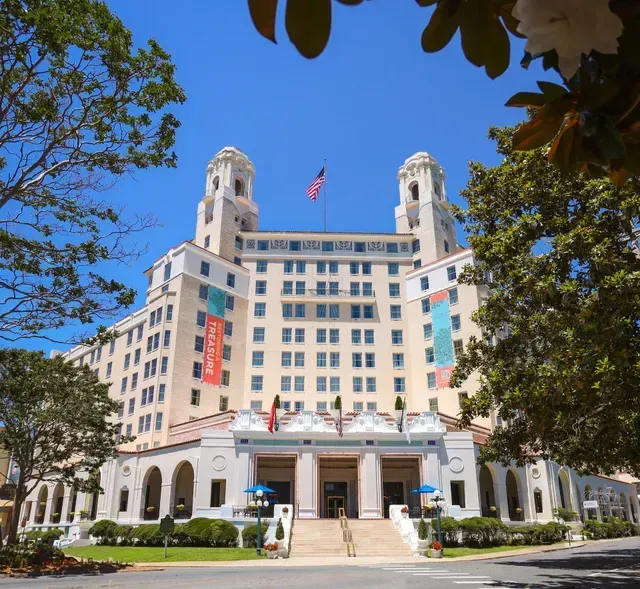 The historic, light-colored Casa Monica Hotel in St. Augustine, Florida, featuring two towers and a central entrance.
