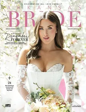 Arkansas Bride magazine cover featuring a person in a white, off-the-shoulder lace wedding gown holding a floral bouquet.