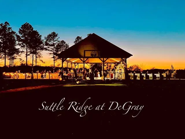 An illuminated wooden pavilion at sunset with the text 