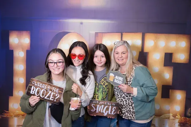 Four people pose together in front of illuminated 