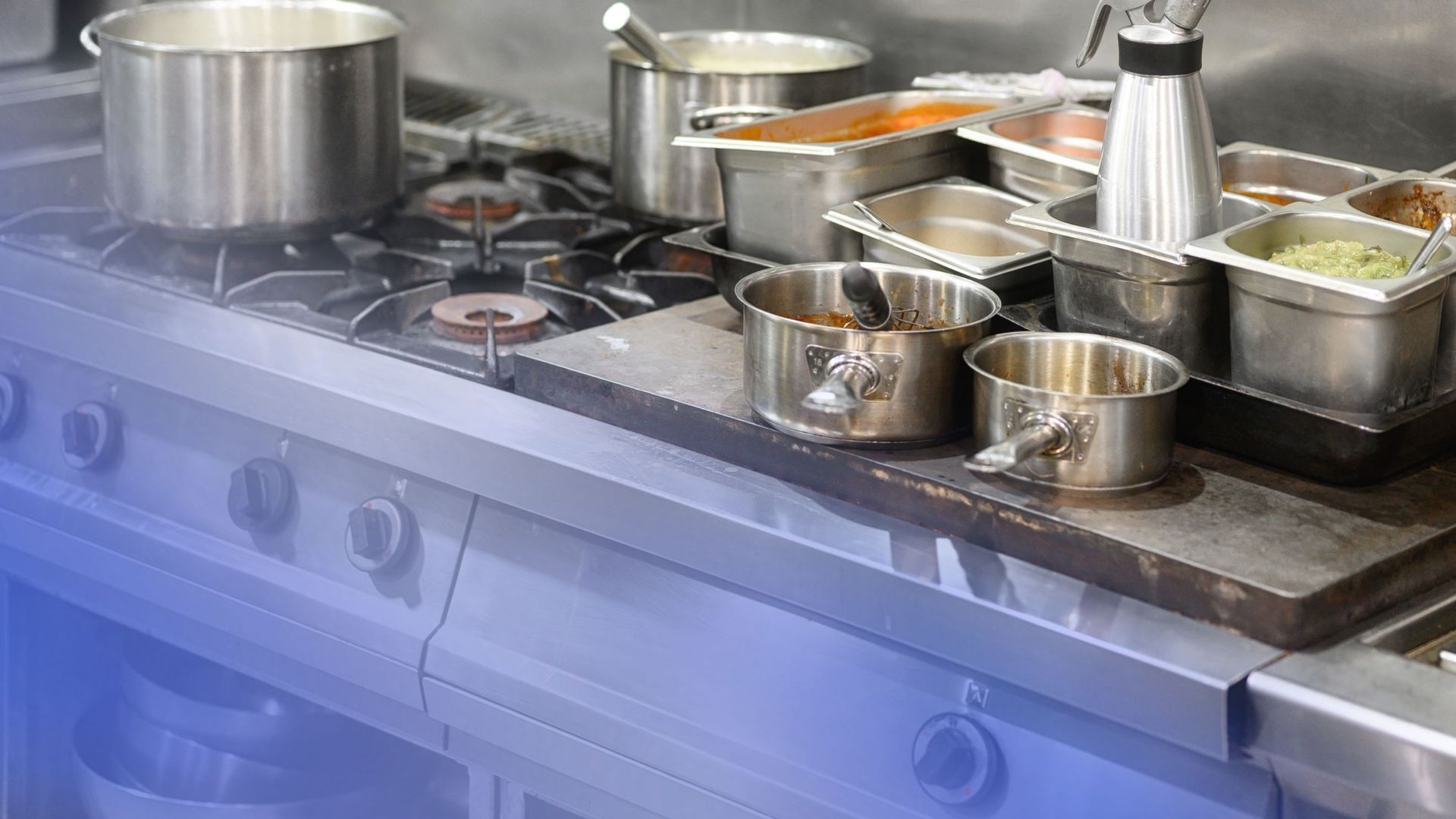 There are many pots and pans on the stove in the kitchen.