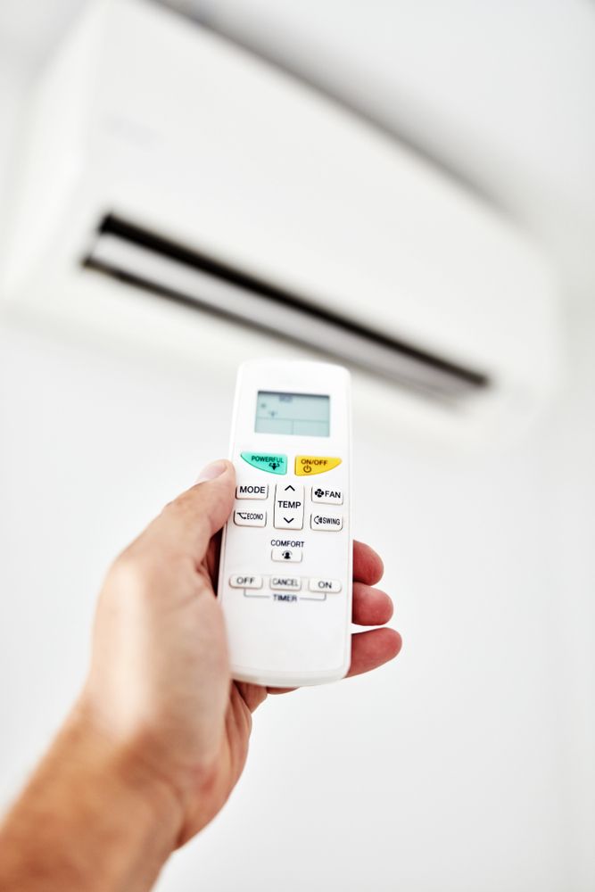 A Person is Holding a Remote Control of an Air Conditioner — Rapidcool Air Conditioning & Electrical in Dapto, NSW