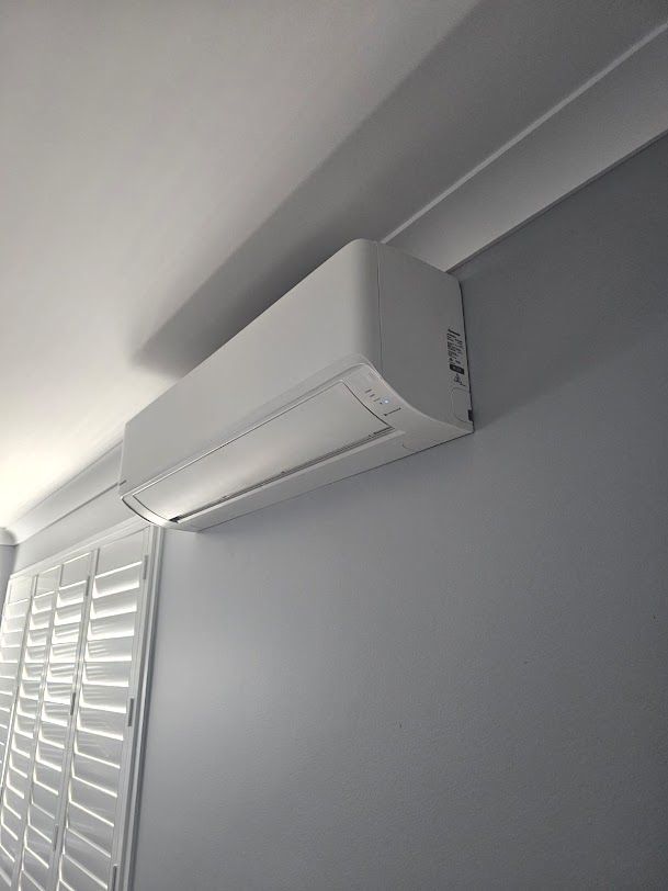 A White Air Conditioner Is Hanging From The Ceiling In A Room — Rapidcool Air Conditioning & Electrical In Dapto, NSW