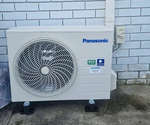 A Panasonic Air Conditioner Is Mounted To A Brick Wall — Rapidcool Air Conditioning & Electrical In Dapto, NSW