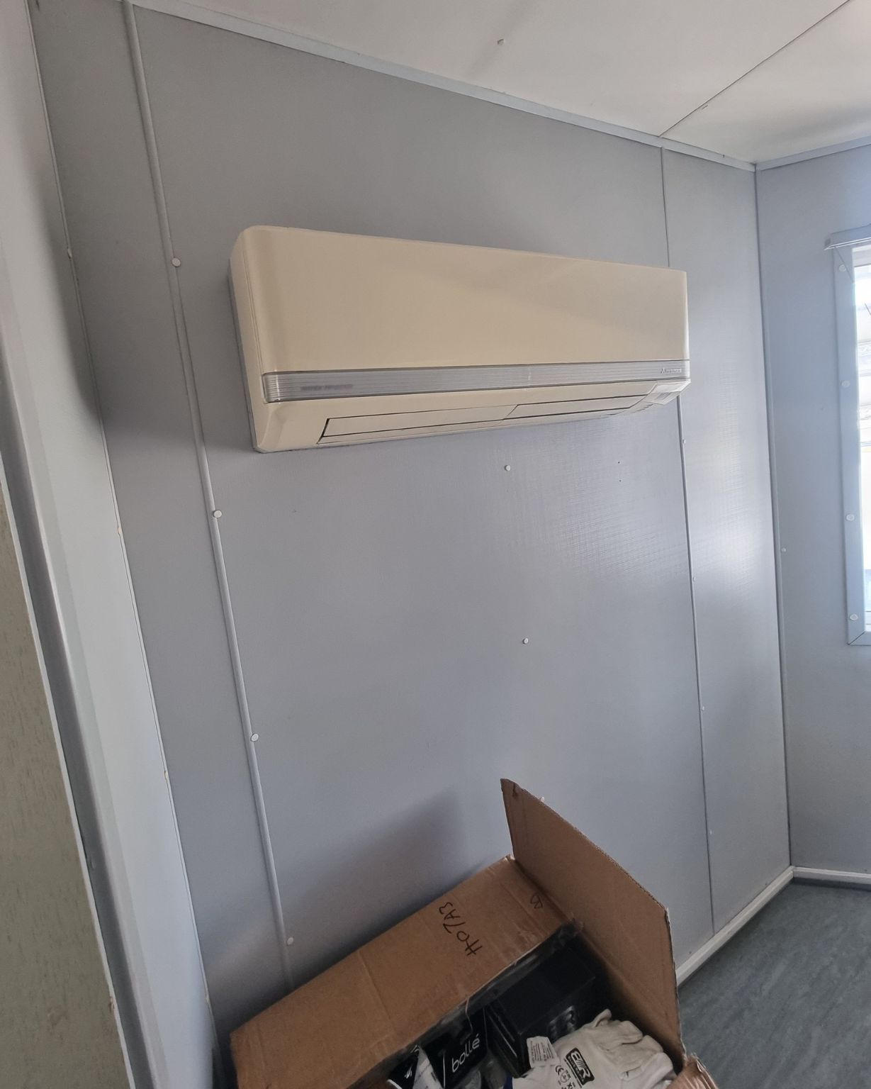 A Room With A Box On The Floor And A Wall Mounted Air Conditioner — Rapidcool Air Conditioning & Electrical In Dapto, NSW