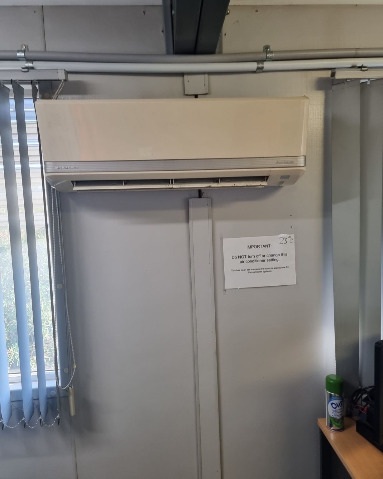 An Air Conditioner Is Hanging On A Wall Next To A Window — Rapidcool Air Conditioning & Electrical In Kiama, NSW