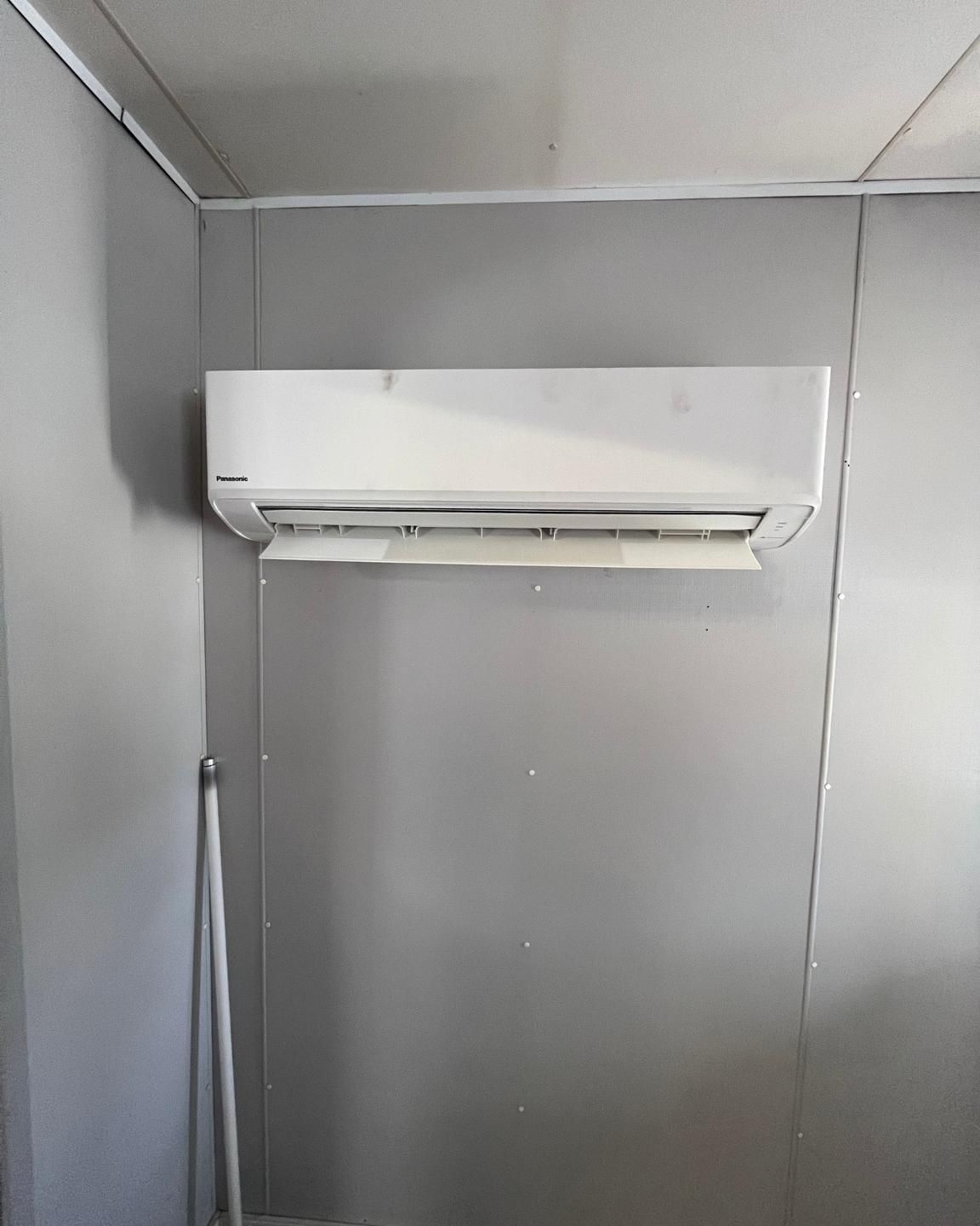 A White Air Conditioner Is Hanging On A Wall In A Room — Rapidcool Air Conditioning & Electrical In Dapto, NSW