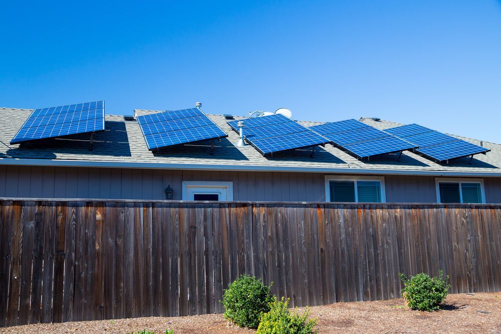 A House With A Wooden Fence And Solar Panels On The Roof — Rapidcool Air Conditioning & Electrical In Wollongong, NSW