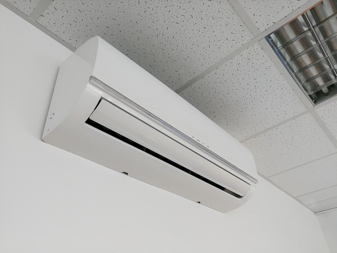 A White Air Conditioner is Mounted to a White Wall — Rapidcool Air Conditioning & Electrical in Dapto, NSW