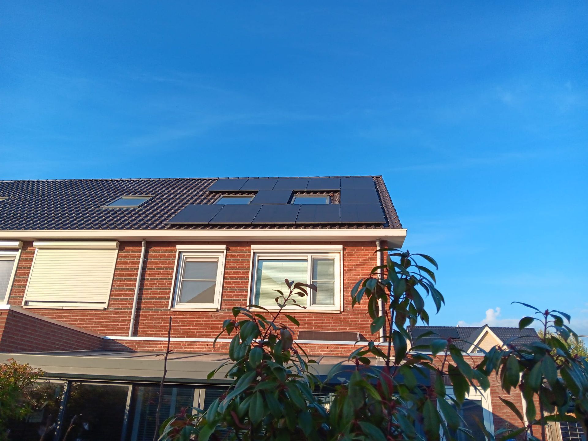 Een bakstenen huis met zonnepanelen op het dak.