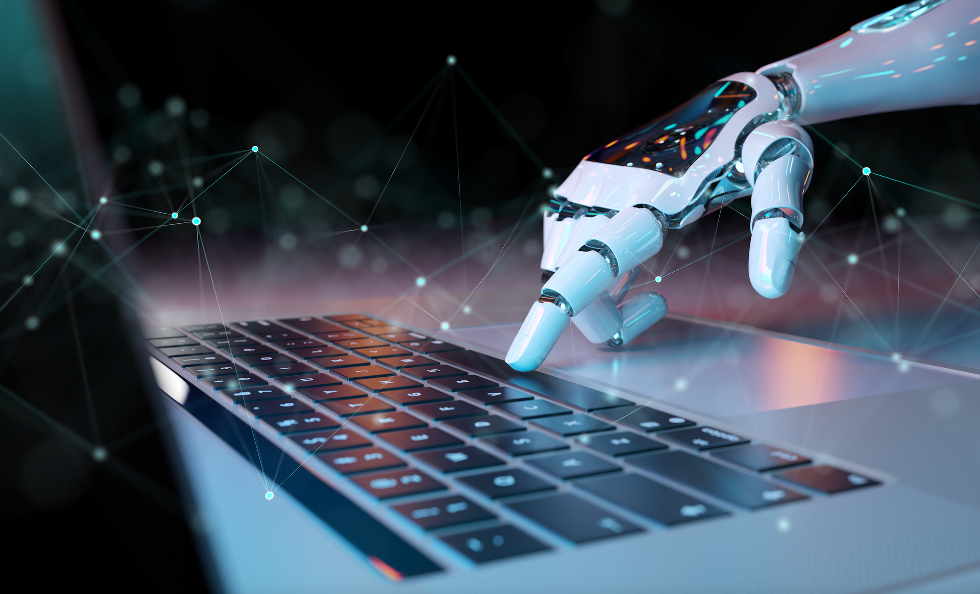 A robotic hand is typing on a laptop computer.