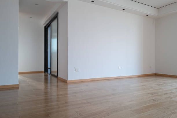 An empty room with hardwood floors and white walls.