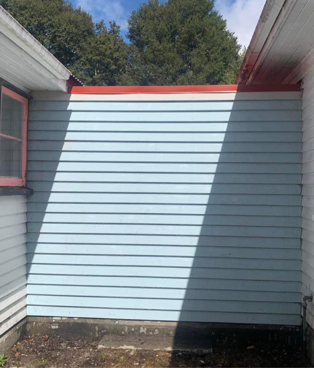 A blue siding on the side of a house with a red trim.