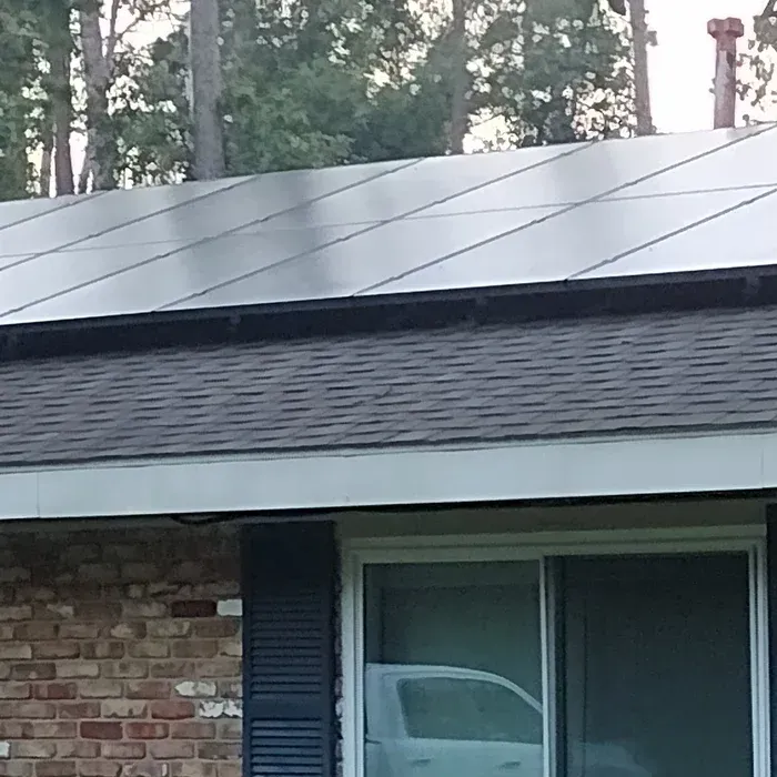 Solar panels on a residential roof, with a brick facade and window visible.