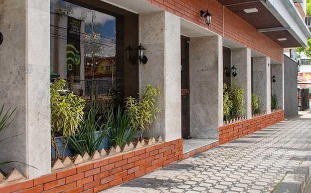 Fachada do edifício com vitrine, base de tijolos e vasos de plantas.