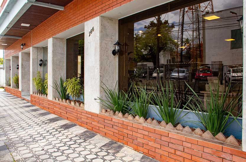 Exterior do edifício com fachada de tijolos e grandes janelas que refletem a paisagem externa.