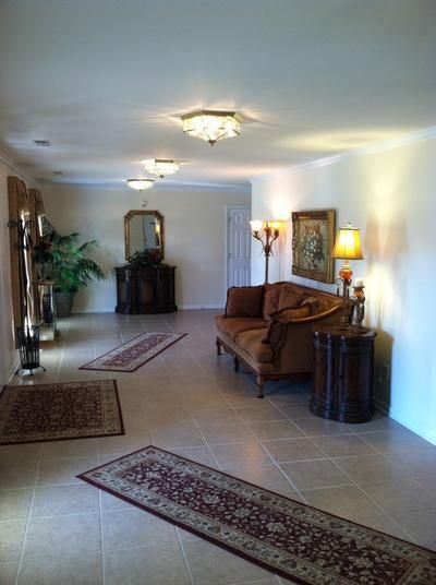 Long hallway with tiled floor, antique furniture, rugs, and decorative lighting.