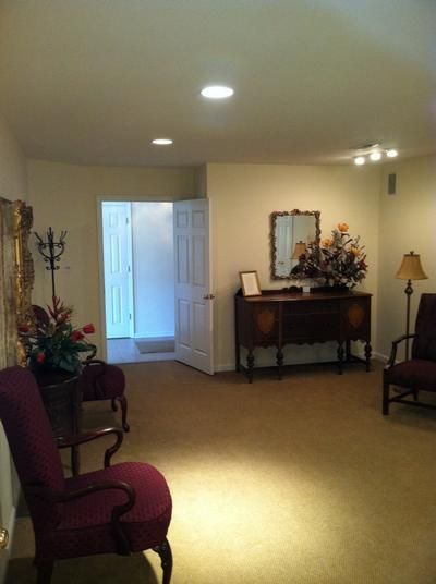 Interior of a room with chairs, a mirror, and a door; beige walls and carpet.