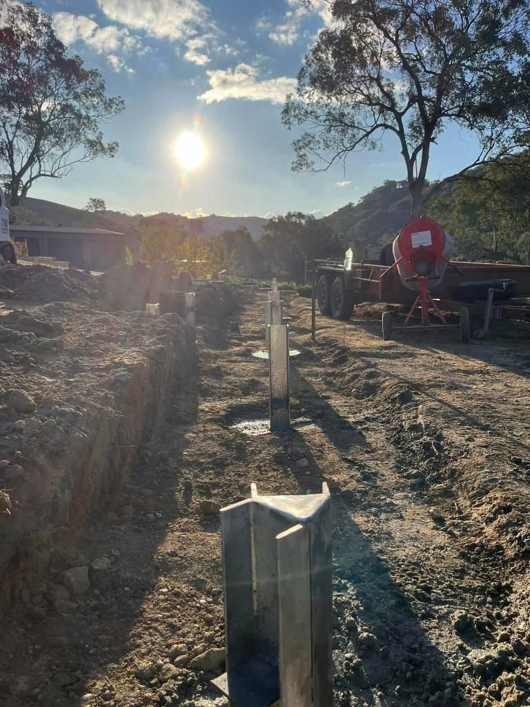 Row of Metal Poles Are Sitting in the Dirt on a Dirt Road — Donaldson Plumbing & Excavations in Chiltern, VIC