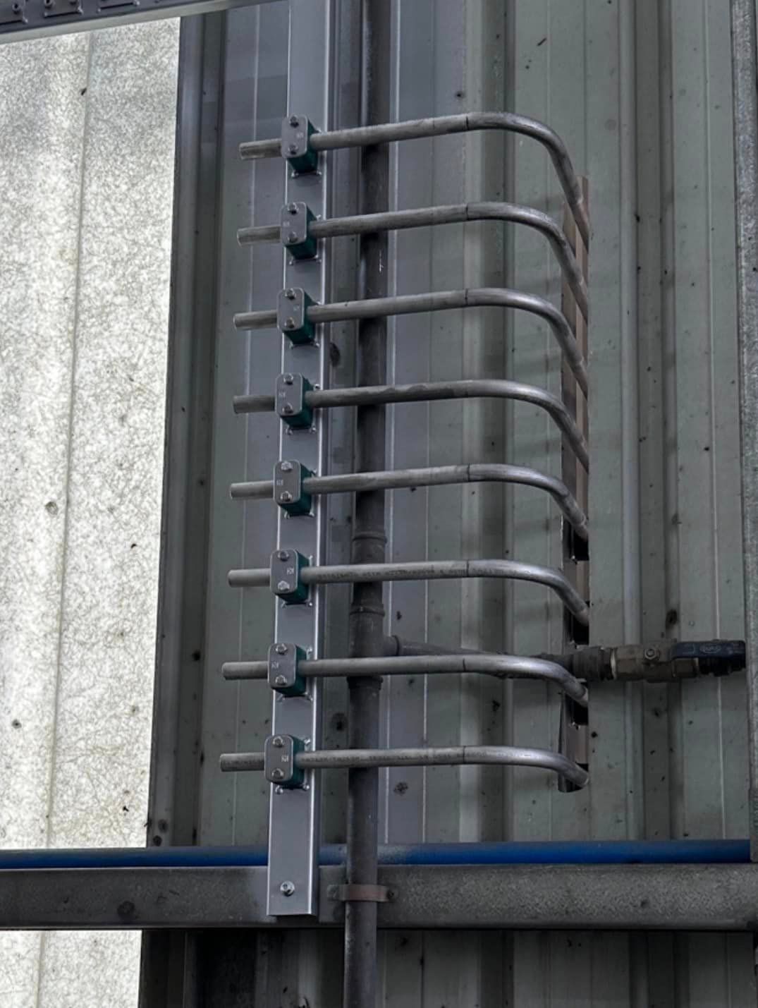 Row of Metal Pipes Are Attached to a Wall — Donaldson Plumbing & Excavations in Kergunyah, VIC