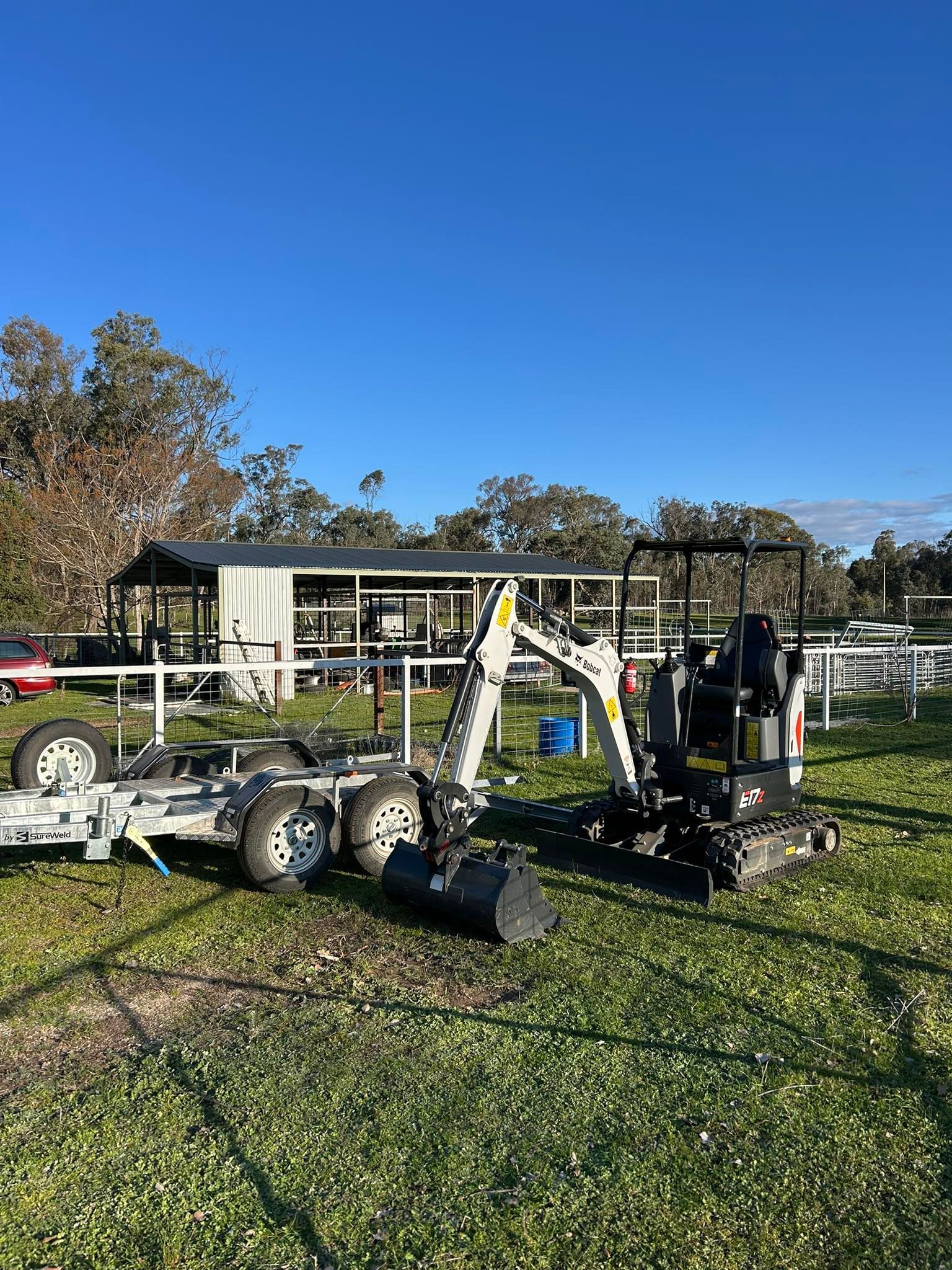 Mini Excavator and Trailer Parked on Grass — Donaldson Plumbing & Excavations in Baranduda, VIC