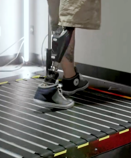 Person walking on a treadmill with a lower-leg prosthetic attached to the left leg