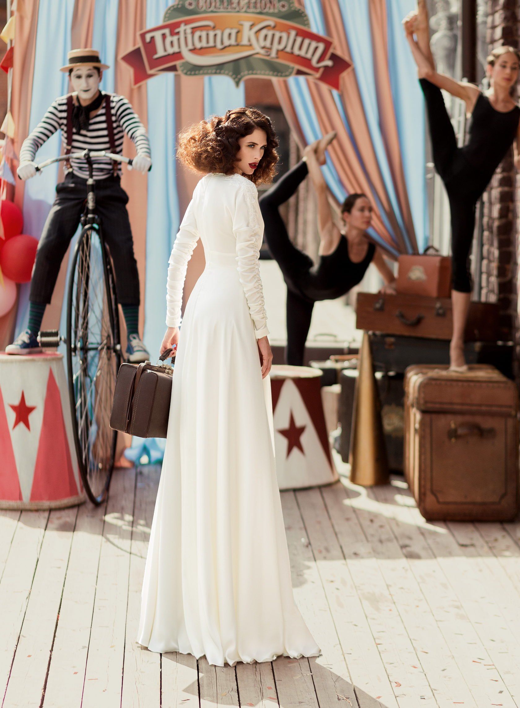 Eine Frau in einem weißen Kleid steht vor einem Schild mit der Aufschrift „Tatiana Kaplan“