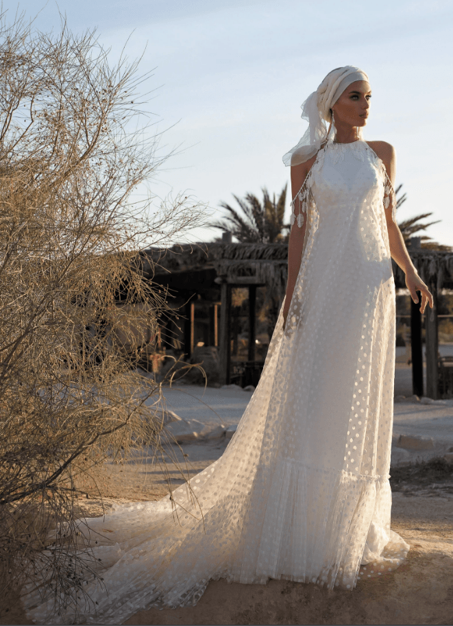 Eine Frau in einem weißen Brautkleid steht in der Wüste.
