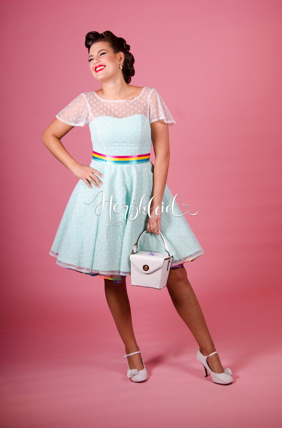 Eine Frau in einem hellblauen Kleid hält eine weiße Handtasche.