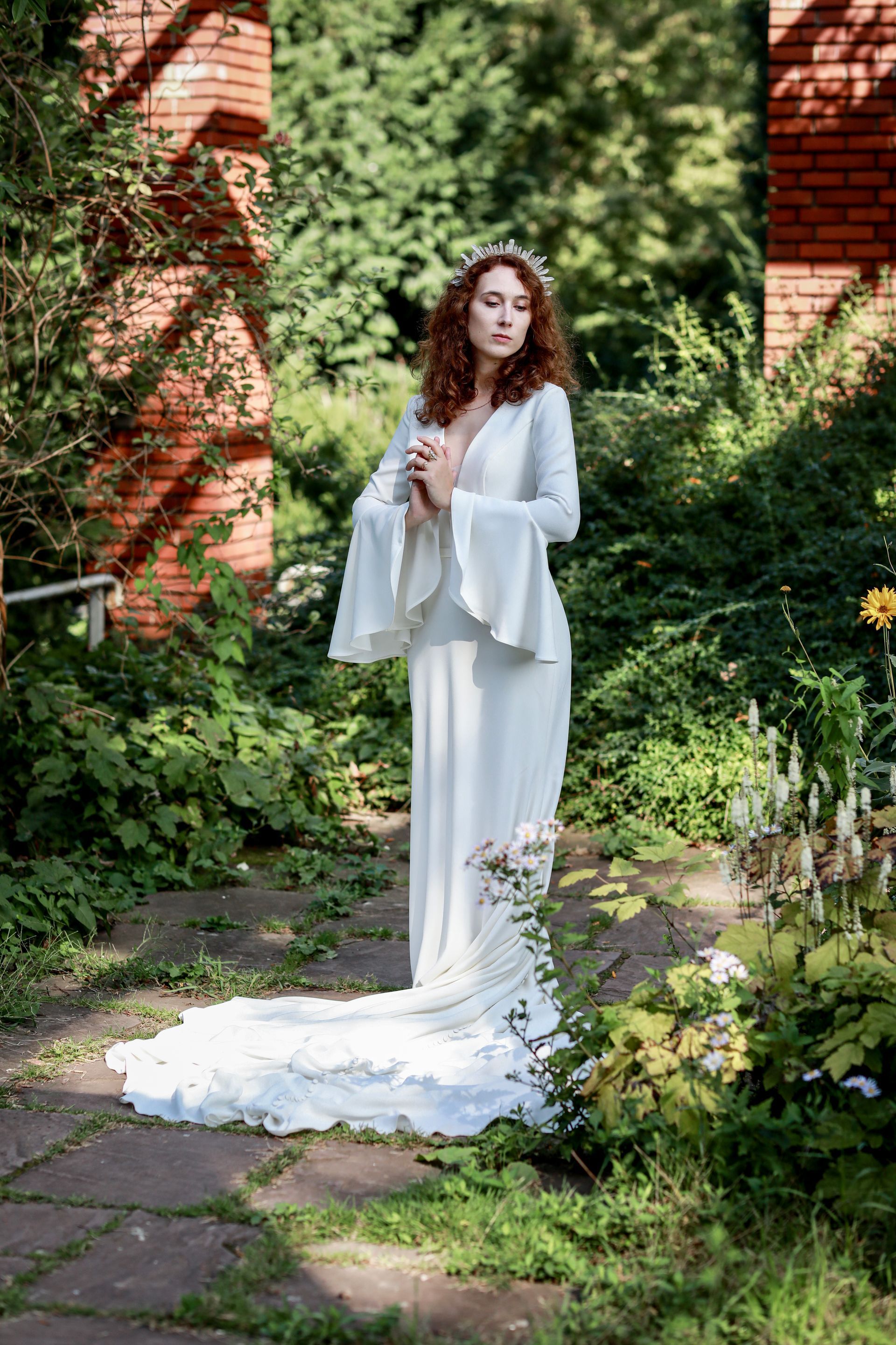 Eine Frau in einem weißen Kleid steht in einem Garten.