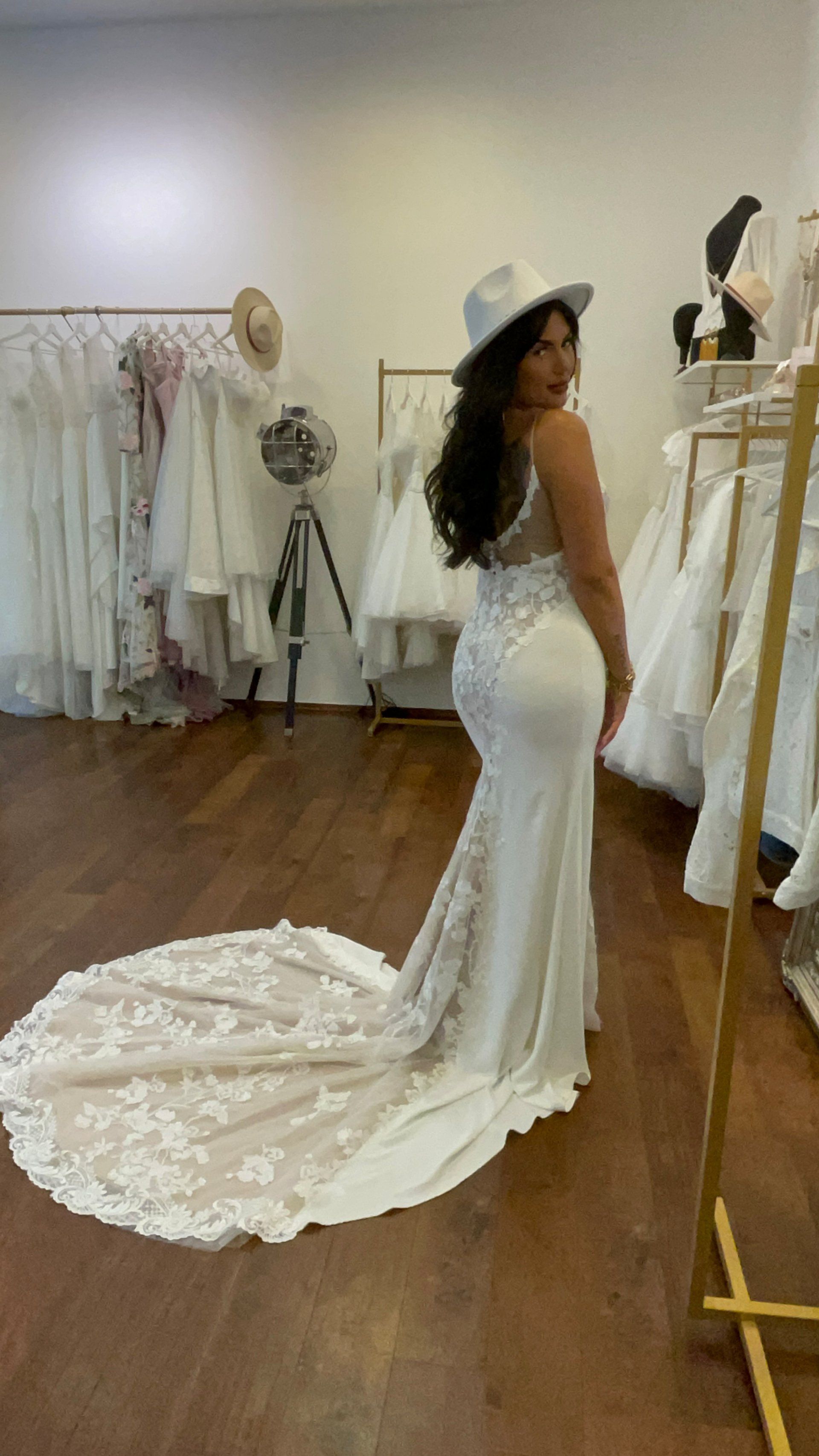 Eine Frau steht in einem Raum und trägt ein Brautkleid und einen Hut.
