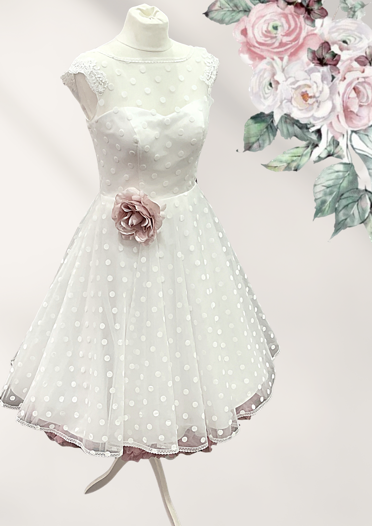 Auf einer Schaufensterpuppe hängt ein weißes Kleid mit Punkten und einer Blume an der Taille.