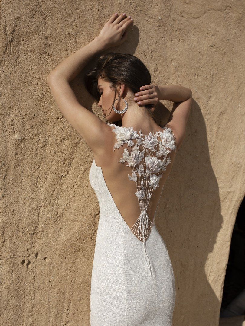 Eine Frau in einem weißen Kleid steht vor einer Wand