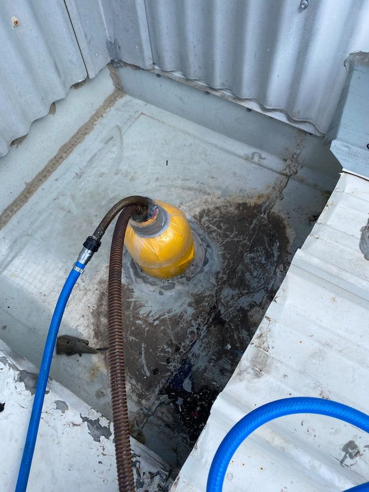 A Hose is Connected to a Yellow Object in a Hole in the Floor — FlowWise in Maroochydore, QLD