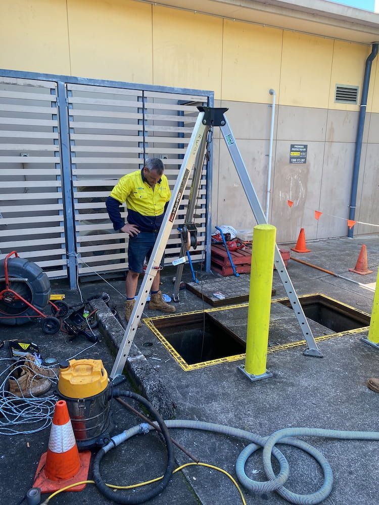 A Man is Standing Next to a Ladder Next to a Hole in the Ground — FlowWise in Maroochydore, QLD