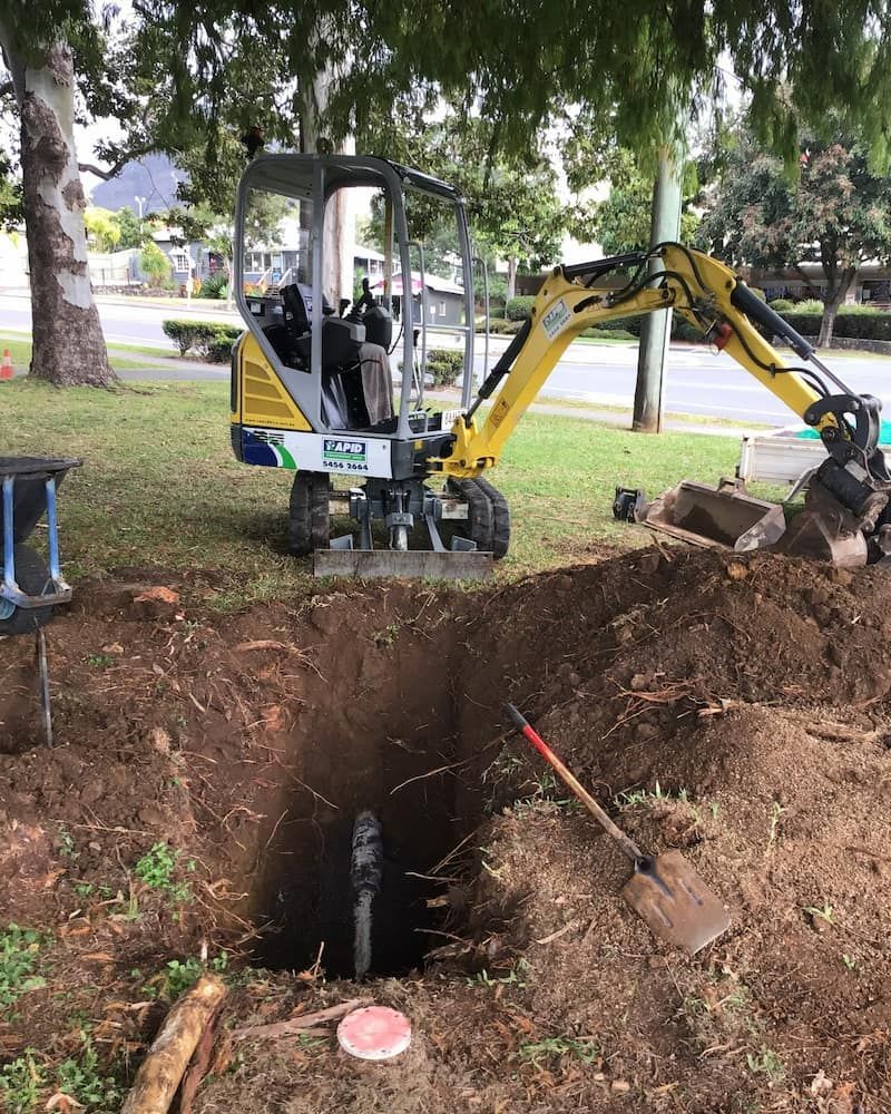 A Small Yellow Excavator is Digging a Hole in the Ground — FlowWise in Maroochydore, QLD