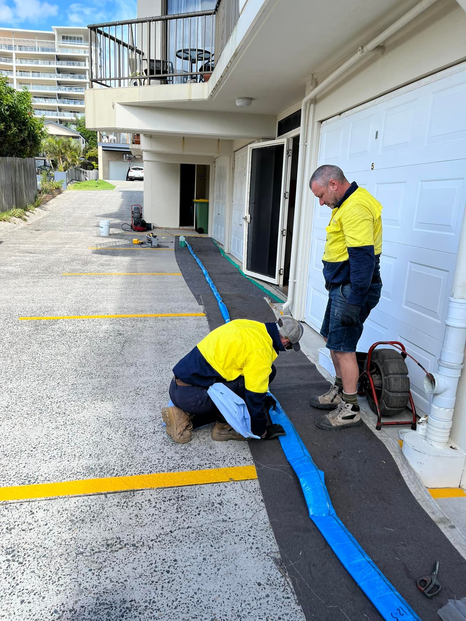 A Man is Standing Next to a Large Hose on a Sidewalk — FlowWise in Maroochydore, QLD