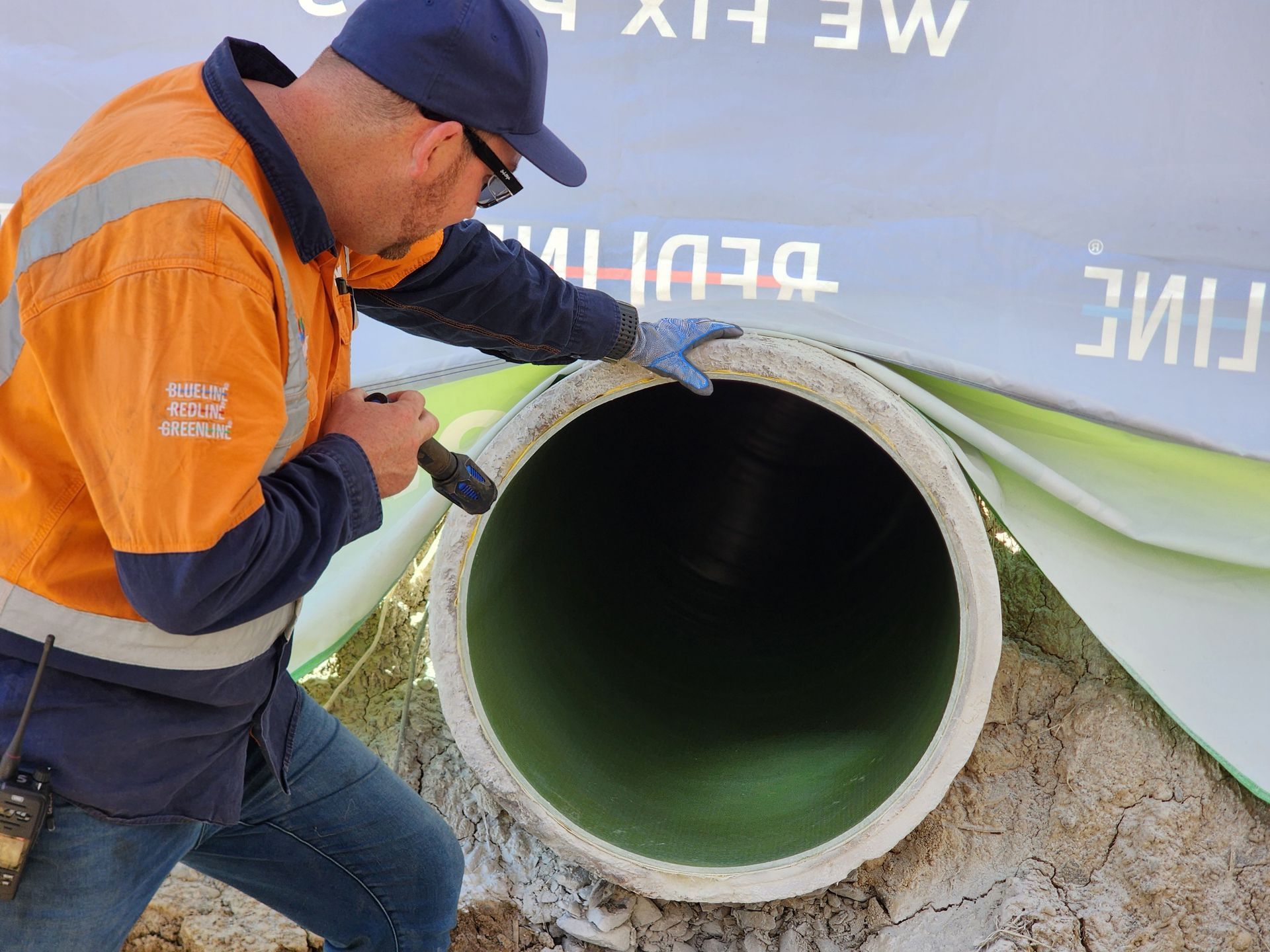 A Man in an Orange Vest is Working on a Pipe — FlowWise in Maroochydore, QLD