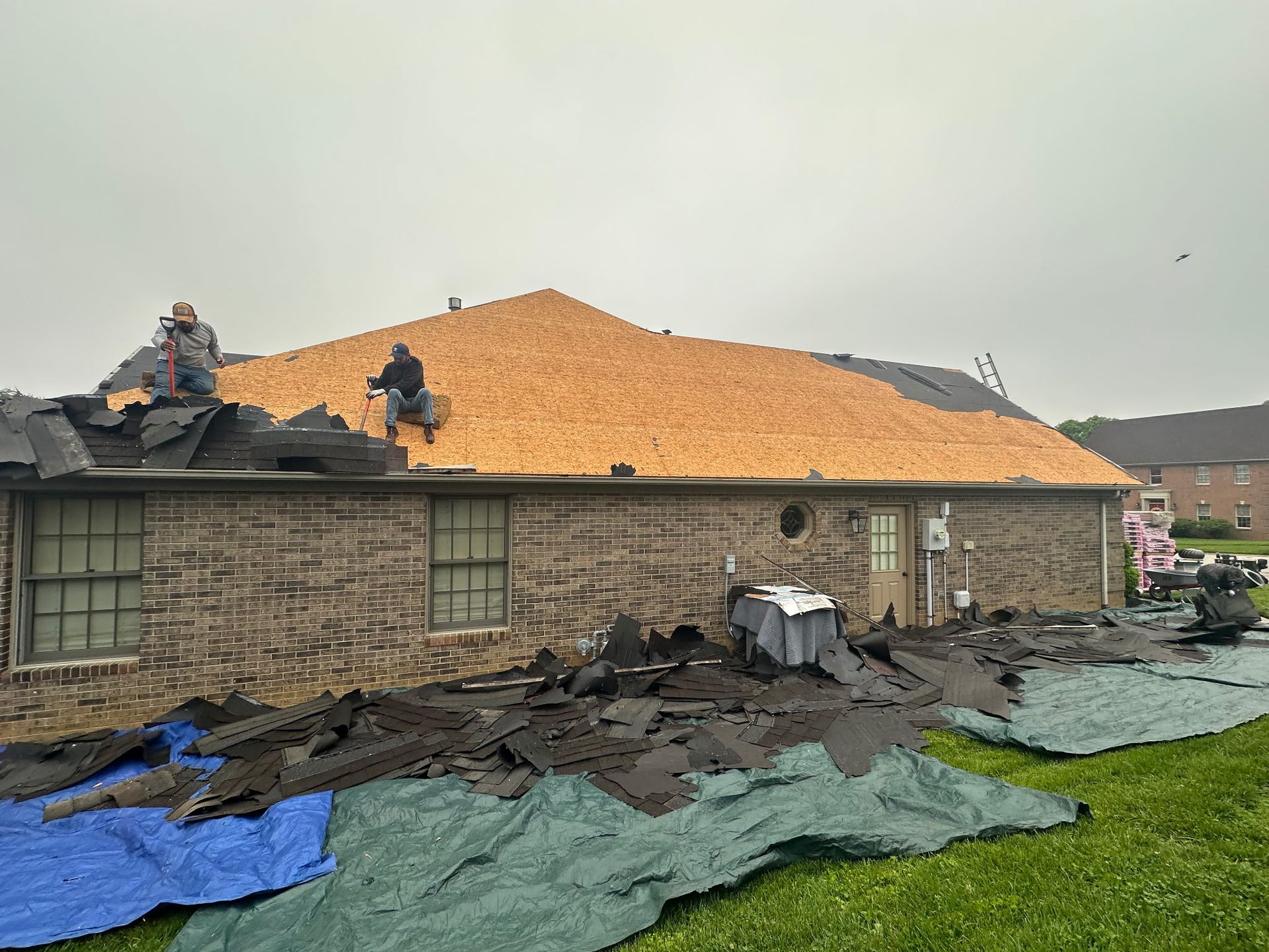 A house is being remodeled with a large pile of shingles on the roof.